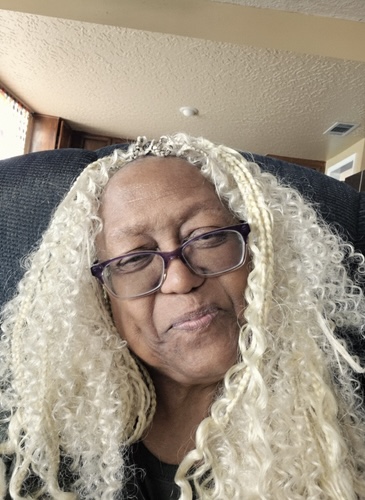 Iris J Hill-Baker. Founder of Wealth Health Beauty Shop. Iris J Hill-Baker. Founder of Wealth Health Beauty Shop sitting in a dark chair in her office, smiling and looking at the viewer. Call (810) 588-0068